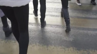 Şehir sakinleri ıslak yaya geçidi boyunca yürüyorlar.