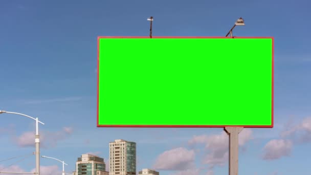 Зеленый рекламный щит против современных вершин зданий и голубого неба — стоковое видео