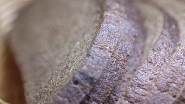 Нарізаний житній хліб лежить у плетеному кошику, що стоїть на столі — стокове відео