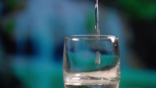 Personne verse de l'eau dans du verre transparent formant des bulles — Video