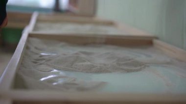 Çocuk boş zamanlarını animasyon masasına kum dökerek geçiriyor.