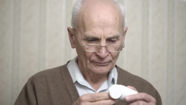 Homem velho na jaqueta marrom abre jarra para tomar remédio no quarto — Vídeo de Stock