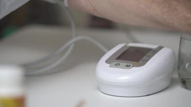 Son sınıf öğrencisi masadaki kan basıncı monitöründe düğmeye basıyor.