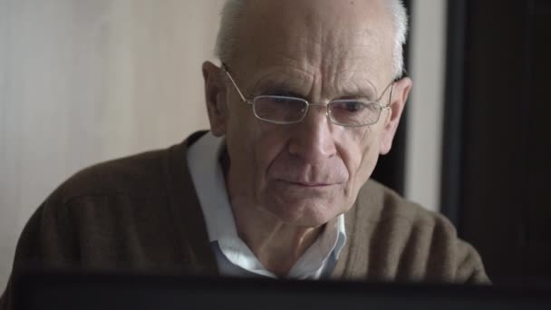 Velho homem careca senta-se no computador e procura conselhos saudáveis — Vídeo de Stock