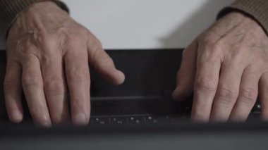 Yaşlı adam not defteri tuşlarına yazıp akrabalarıyla sohbet ediyor.