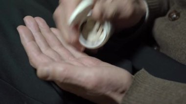 Son sınıf öğrencisi, kavanozdaki yakın plandan avuç içine beyaz haplar koyar.