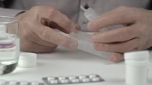 Oude man handen nemen kleine pillen uit tablet blister closeup — Stockvideo