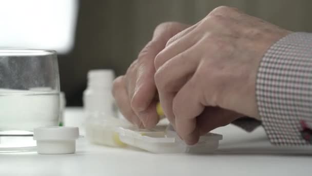 Senior muž vrásčité ruce třídit jasně žluté tablety — Stock video