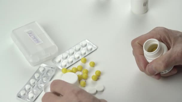 Homem idoso toma pílulas amarelas brilhantes e coloca em garrafa — Vídeo de Stock