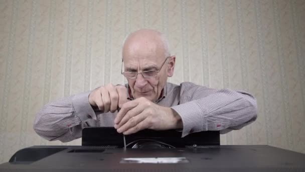 Aged bald man unscrews outdated black television set cover — Αρχείο Βίντεο