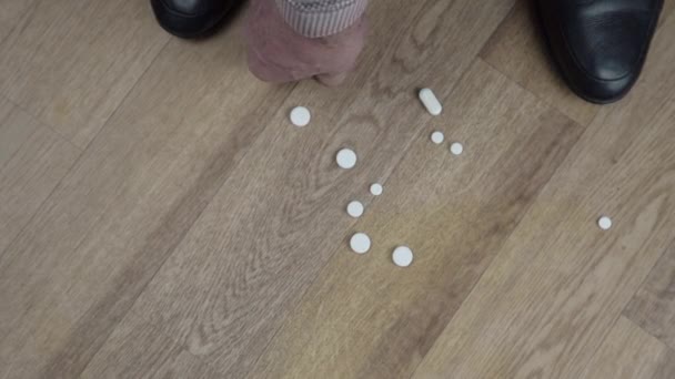 Stařec ruce sbírat pilulky jiného tvaru z podlahy — Stock video