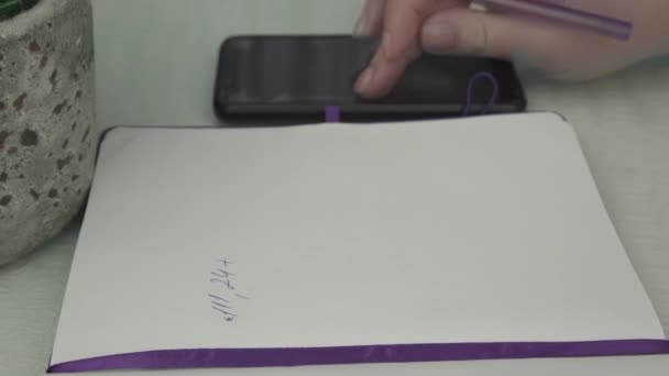 Jeune femme écrit sur la page carnet papier avec stylo violet — Video