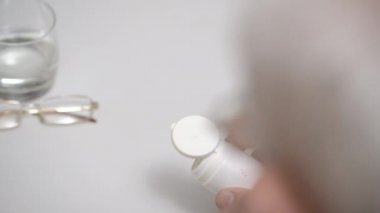 Gözlüklü son sınıf öğrencisi hapları masaya yakın bir yere döker.