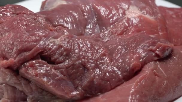 Kawałki świeżego surowego soczystego mięsa wołowego obracają się na talerzu makro — Wideo stockowe