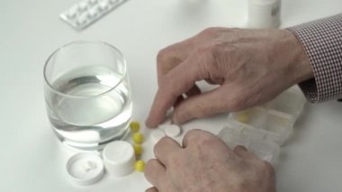 Yaşlı adam hapları özel plastik konteynırlarda sınıflandırıyor.