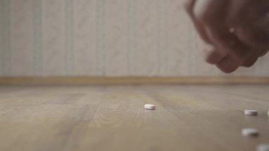 Yaşlı emekli, kahverengi zeminden beyaz ilaç topluyor