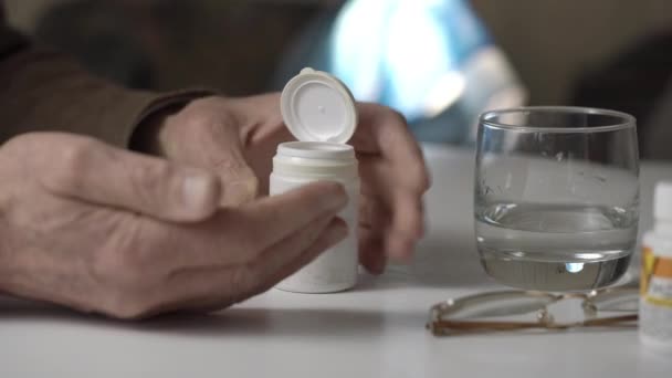 Malato uomo anziano prende medicina con acqua a tavola primo piano — Video Stock