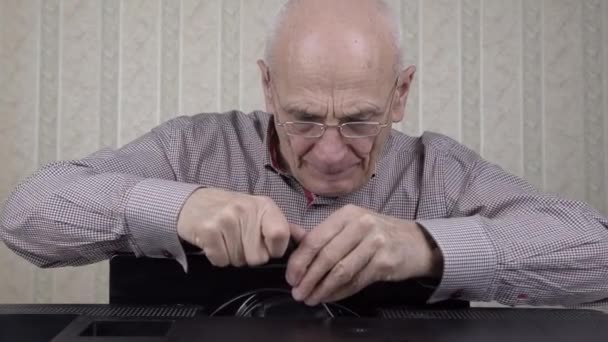 Ingenieur mit Glatze schraubt veralteten schwarzen Fernseher im Zimmer ab — Stockvideo