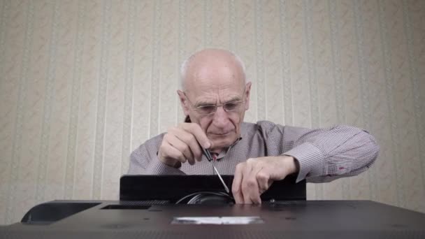 Senior pensionär sätter på glasögon och skruvar TV — Stockvideo