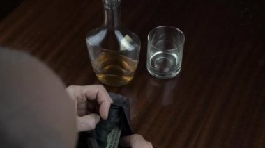 Yaşlı adam elleri cüzdanından ve içkisinden para alır.