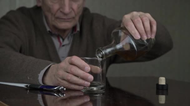 Senior man giet cognac in glas met trillende handen — Stockvideo