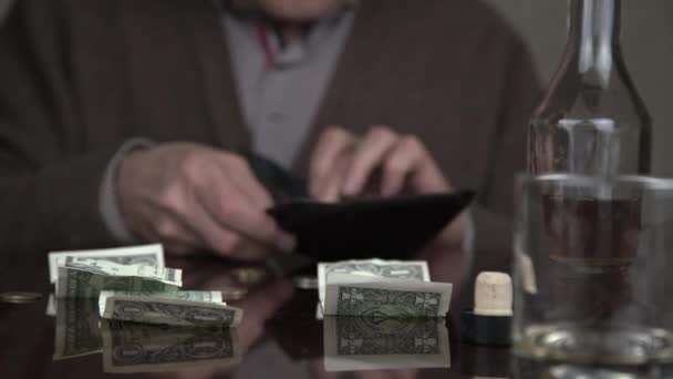 Παλαιωμένος αλκοολικός εξετάζει μαύρο δερμάτινο πορτοφόλι και ποτά — Αρχείο Βίντεο
