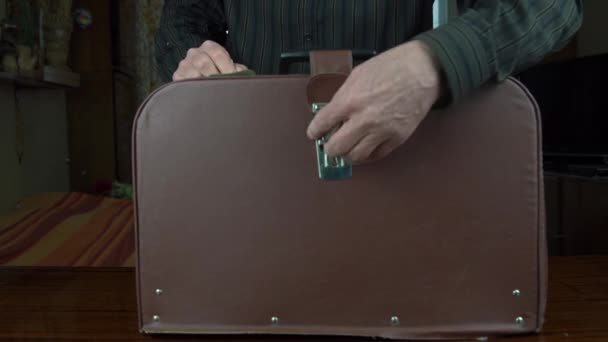 男は革のスーツケースを開きアンティークミシンを拭く — ストック動画