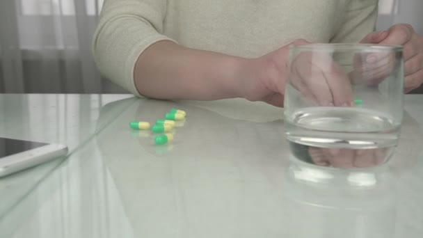 Mano signora con manicure conta pillole verdi gialle sul tavolo — Video Stock