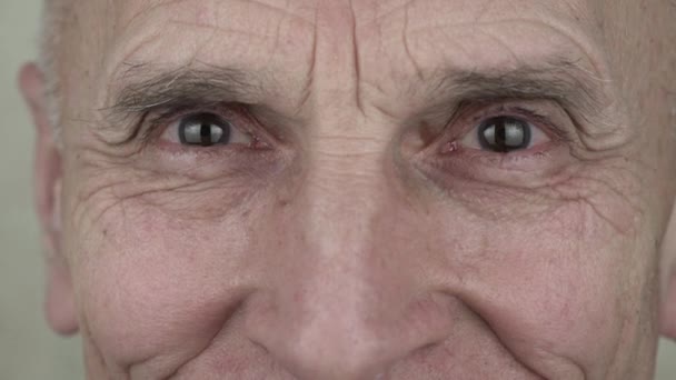 Усміхнений чоловік з мудрим зморщеним обличчям і великими сірими розмитими очима — стокове відео