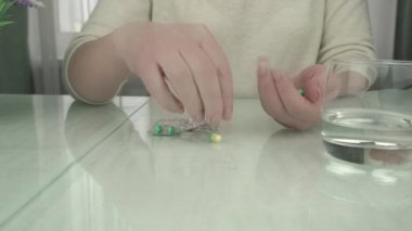 Bayan elinde renkli haplar ve suyla içki topluyor.