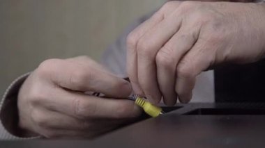 Yaşlı adam el, krikoları eski televizyon paneline bağlıyor