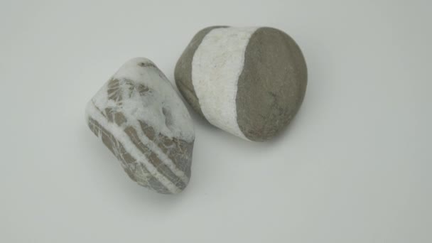 Pebble rocks of grey and white colours lie on light surface — Stock Video