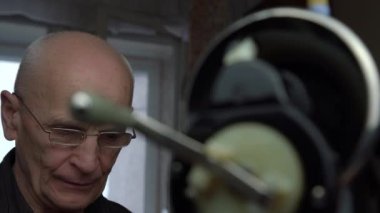Yaşlı adam kumaşı yerinde katlıyor ve düz dikiş atıyor.