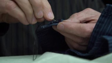 terzi erkek gömleği dikmeyi bitiriyor düğmeleri kapatıyor