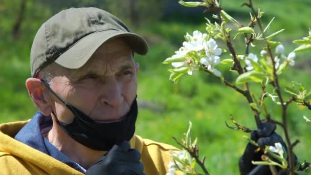 头戴手套的老人摘下带有白花香味的黑色面具 — 图库视频影像