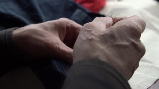 Egyedül öreg kéz varr gombokat meleg ing közelkép — Stock videók