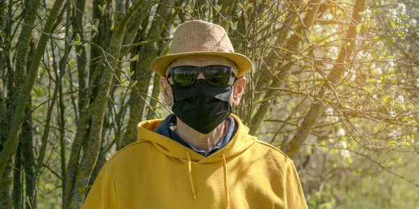 Homem sênior em óculos de sol e máscara descartável por árvores — Fotografia de Stock