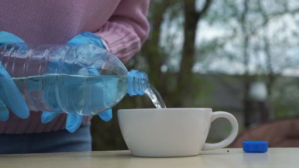 Persona en guantes vierte agua en taza da a las manos temblorosas — Vídeos de Stock