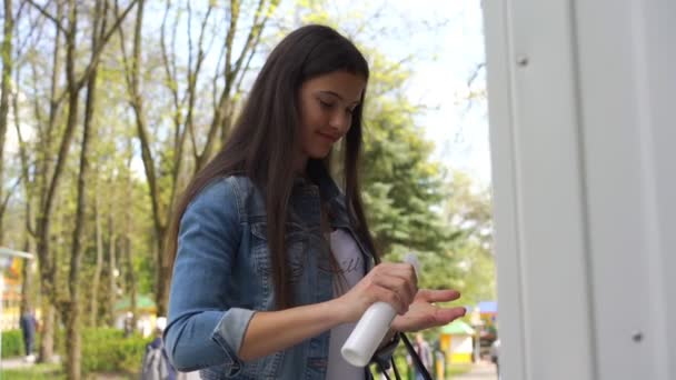 Långhårig brunett i jackor sprayer antiseptisk på händerna — Stockvideo