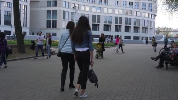 Różne osoby wędrują wzdłuż szarej brukowanej drogi obok budynku — Wideo stockowe