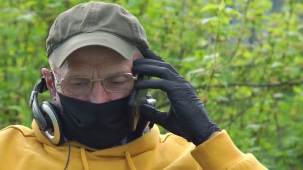 Pensioner na máscara fala no telefone celular no jardim verde — Vídeo de Stock