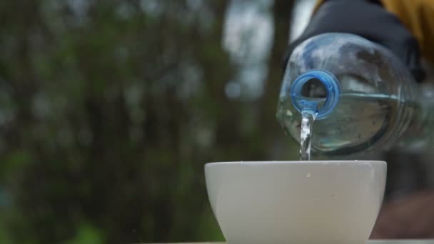 戴无菌手套的老年人把水倒入杯子和饮料中 — 图库视频影像