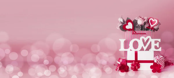ギフトボックス バラの束と心で構成されたバレンタインデーショッピングバッグ 言葉で愛とリボンはボケ フロントビュー バナーと赤ピンクの背景に立って — ストック写真