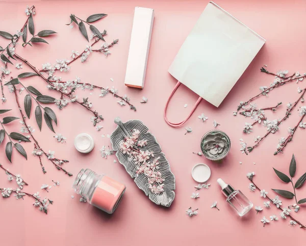 化妆品的概念 采购产品各种面部产品和纸袋在粉红的底色与樱花和叶子 顶视图 复制空间为您的设计 美丽博客的布局 平躺在床上 — 图库照片