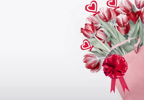 情人节背景 红色郁金香在购物袋装饰有蝴蝶结 缎带和心脏 假日购物的概念 浪漫的花卉作曲 花儿成堆贺卡或优惠券 — 图库照片
