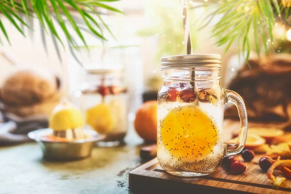 中国の種子と健康的な夏の飲み物は水をデトックス オレンジフルーツスライス レモン汁と材料とキッチンテーブルの上にマソン瓶のクランベリー フィットネスドリンクコンセプト ストック写真