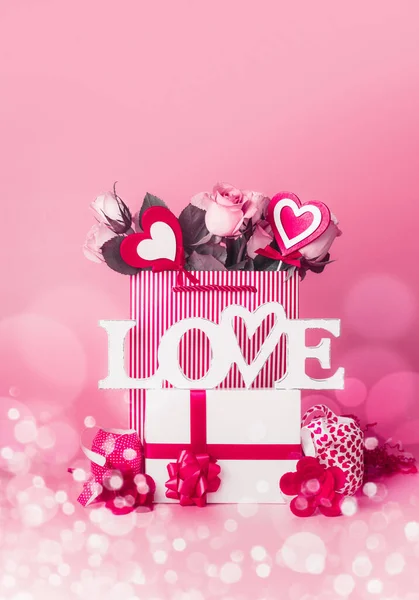 バレンタインデーのコンセプト バラの束と心のショッピングバッグ 言葉でギフトボックス愛とリボンはボケ フロントビューと赤ピンクの背景に立って — ストック写真