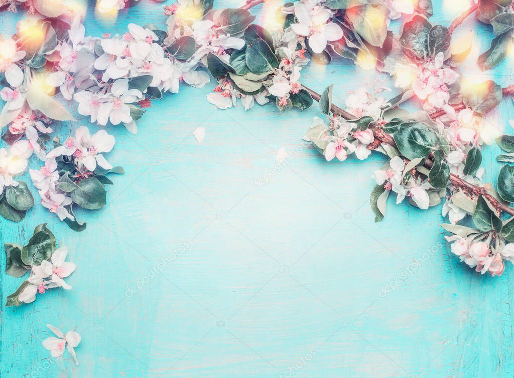 Beautiful spring blossom background with twigs ,flowers and bokeh lighting on blue turquoise wooden background, top view, frame, place for text. Springtime and nature concept