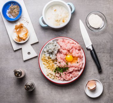 Kıymalı balık köfteleri, yumurta, karides, soğan ve mutfak masasının arka planında bıçaklı, üst manzaralı ıslak ekmek. Deniz ürünleri ve yemek pişirme konsepti