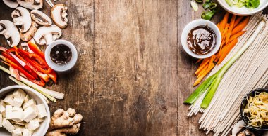 Asyalı vejetaryen yemek malzemeleri tofu, erişte, sebze ve sosla karıştırmak için ahşap arka planda, üst manzara, afiş, çerçeve